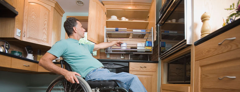Main in wheelchair putting dishes away in his home