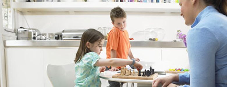 Woman in playing chess with her children